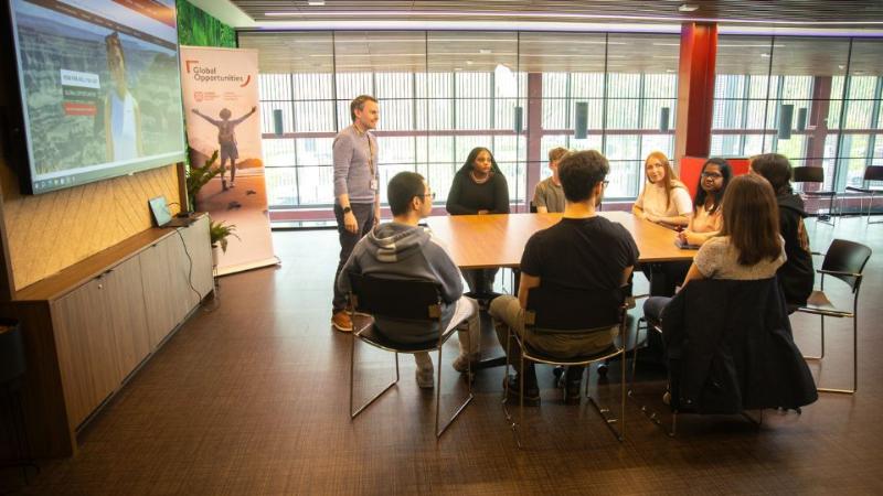 students in a room in a tutorial sitting at a large desk